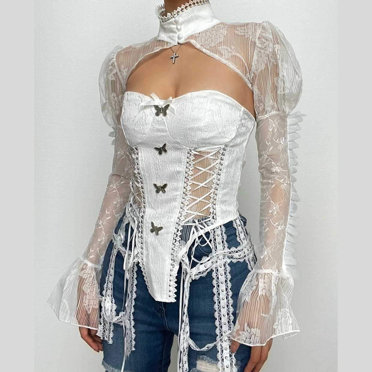 Top de cuello alto con mariposa, manga larga, botones, cordones y cremallera 